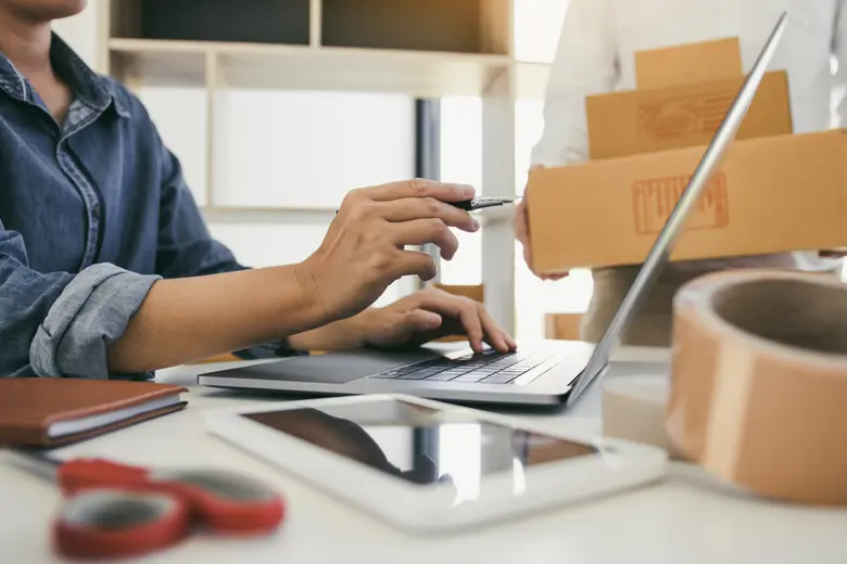 A woman's hand one pointing to her laptop and one on her keyboard.