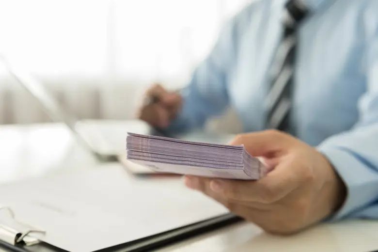 A man's hand holding a stash of paper bill.