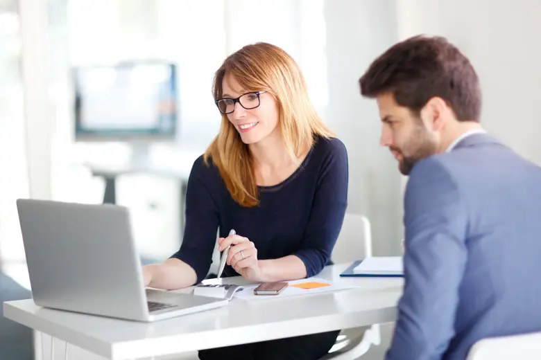 A professional working woman showing a professional working man her laptop screen.