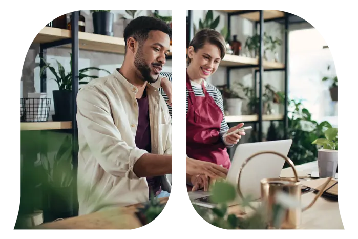 A working man showing a working woman his laptop screen in a plant store.