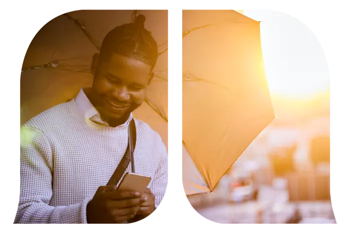 A man with an umbrella looking down at his phone.
