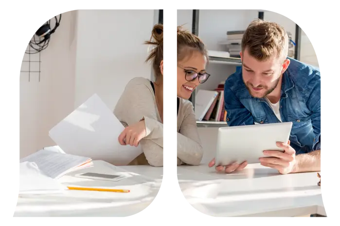 A working man showing his table to a working woman who is holding paper.