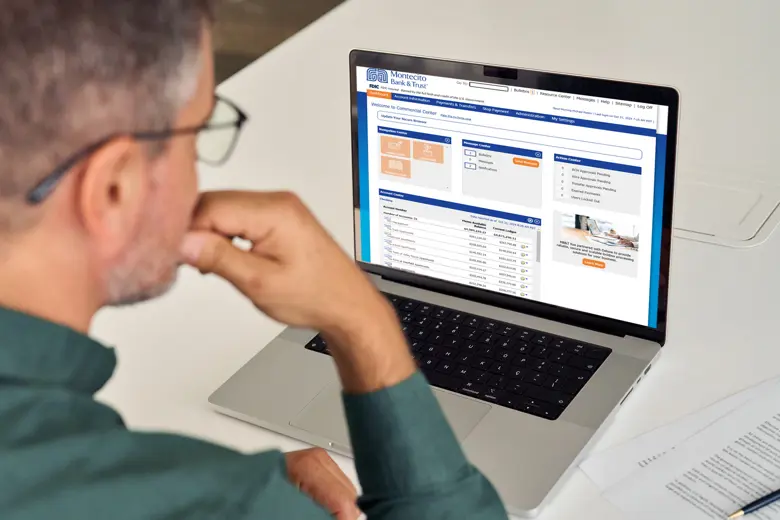 A man looking at his Montecito Bank and Trust account on his laptop.