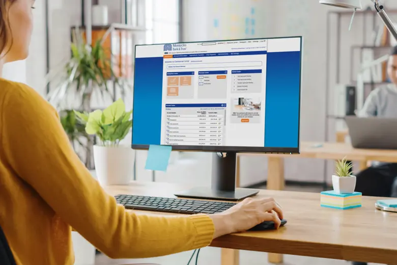 A woman using a desktop that is displaying Montecito Bank and Trust account.