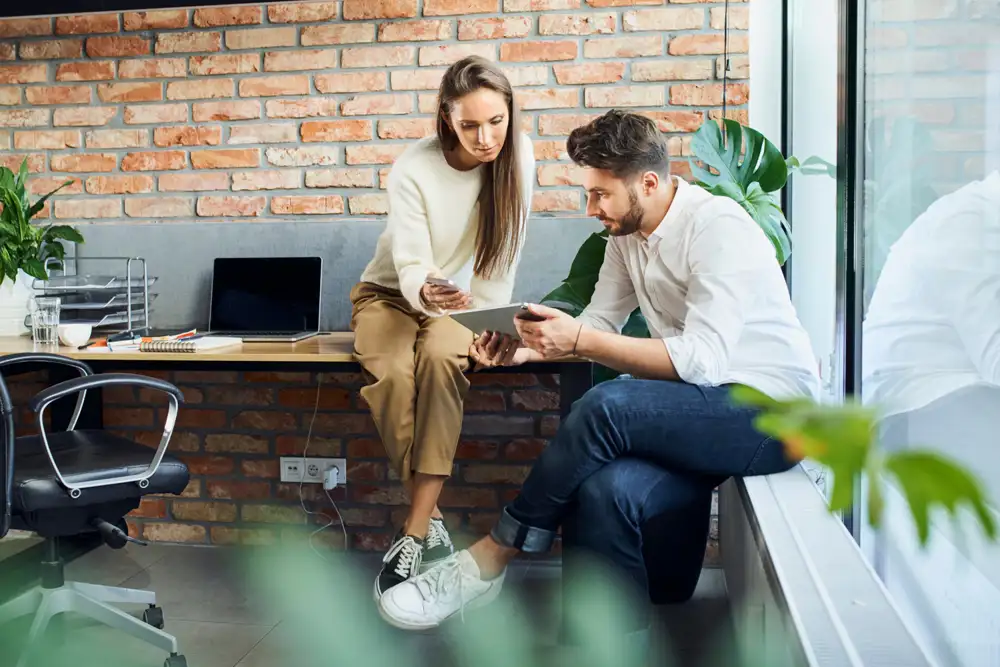 A man showing his tablet to a woman and woman showing her phone to a man.