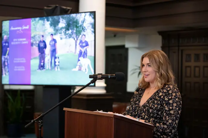 A bank employee gives a speech at a podium to discuss a local nonprofit voted to receive a grant.