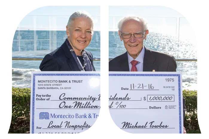 Two bank associates pose with a large check with a million-dollar amount addressed to local nonprofits.