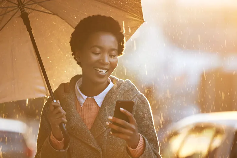 A woman with umbrella looking at her phone.