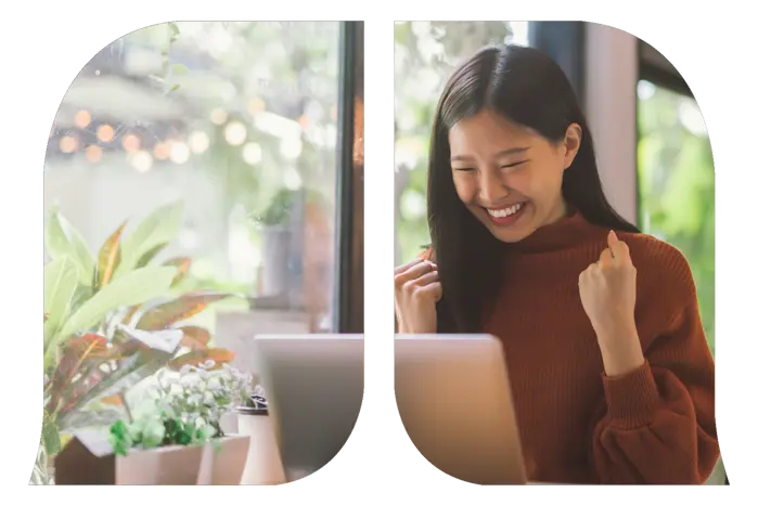 A young woman happily fist pumping as she's looking at her laptop.
