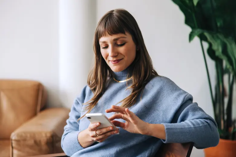A woman sitting on a couch using her phone.