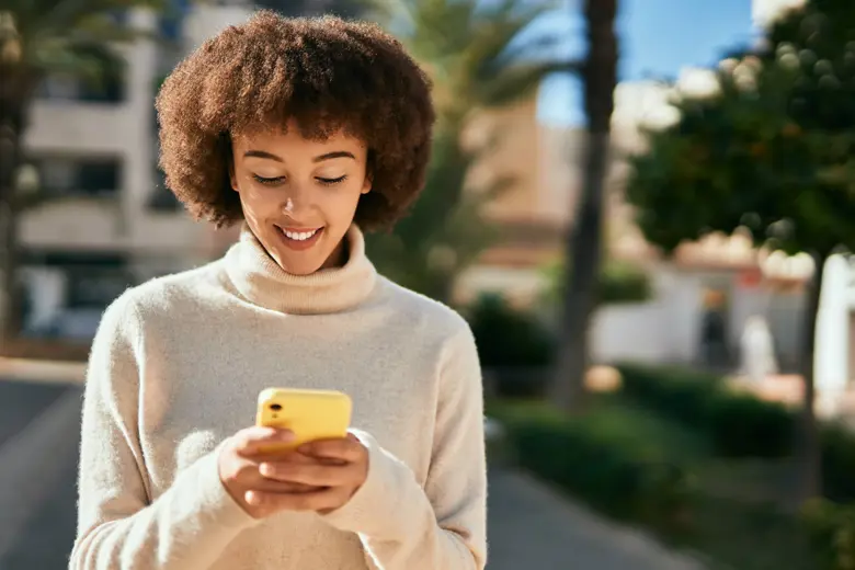 A woman using her phone as she's walking down the street.