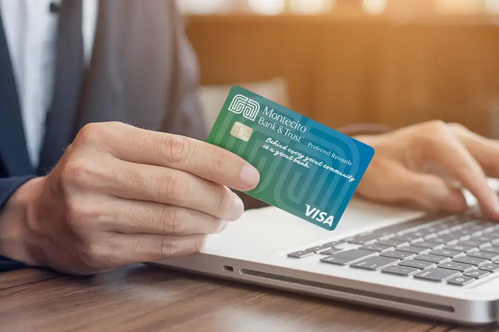 A man's hand holding Montecito Bank and Trust personal credit card.