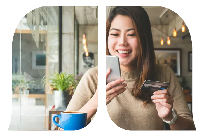 A woman who is looking at her phone with one hand and holding a credit card on the other hand.
