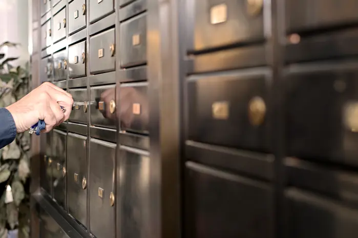 A close-up of deposit boxes with someone opening one.